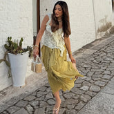Woman in a yellow dress walking on a stone street with a white building in the background